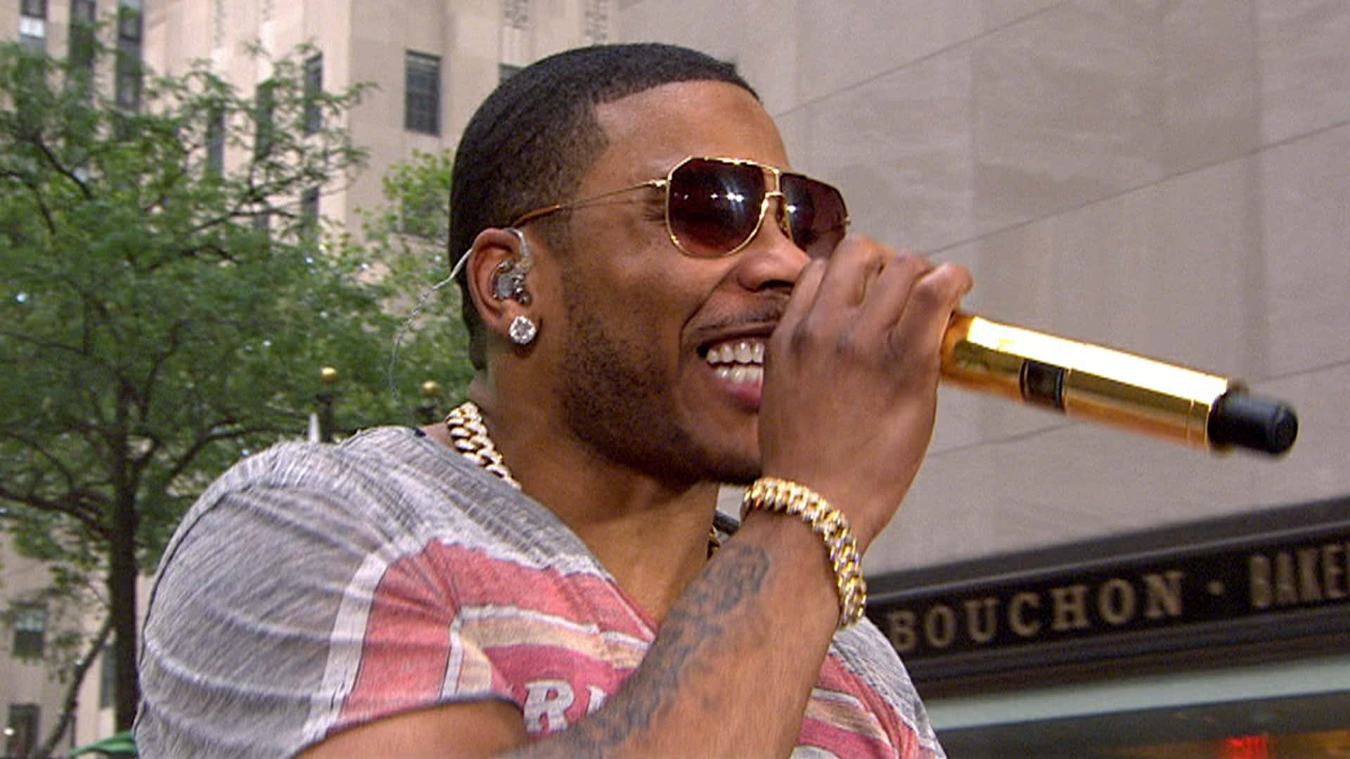 A Man In Sunglasses Is Holding A Microphone Background