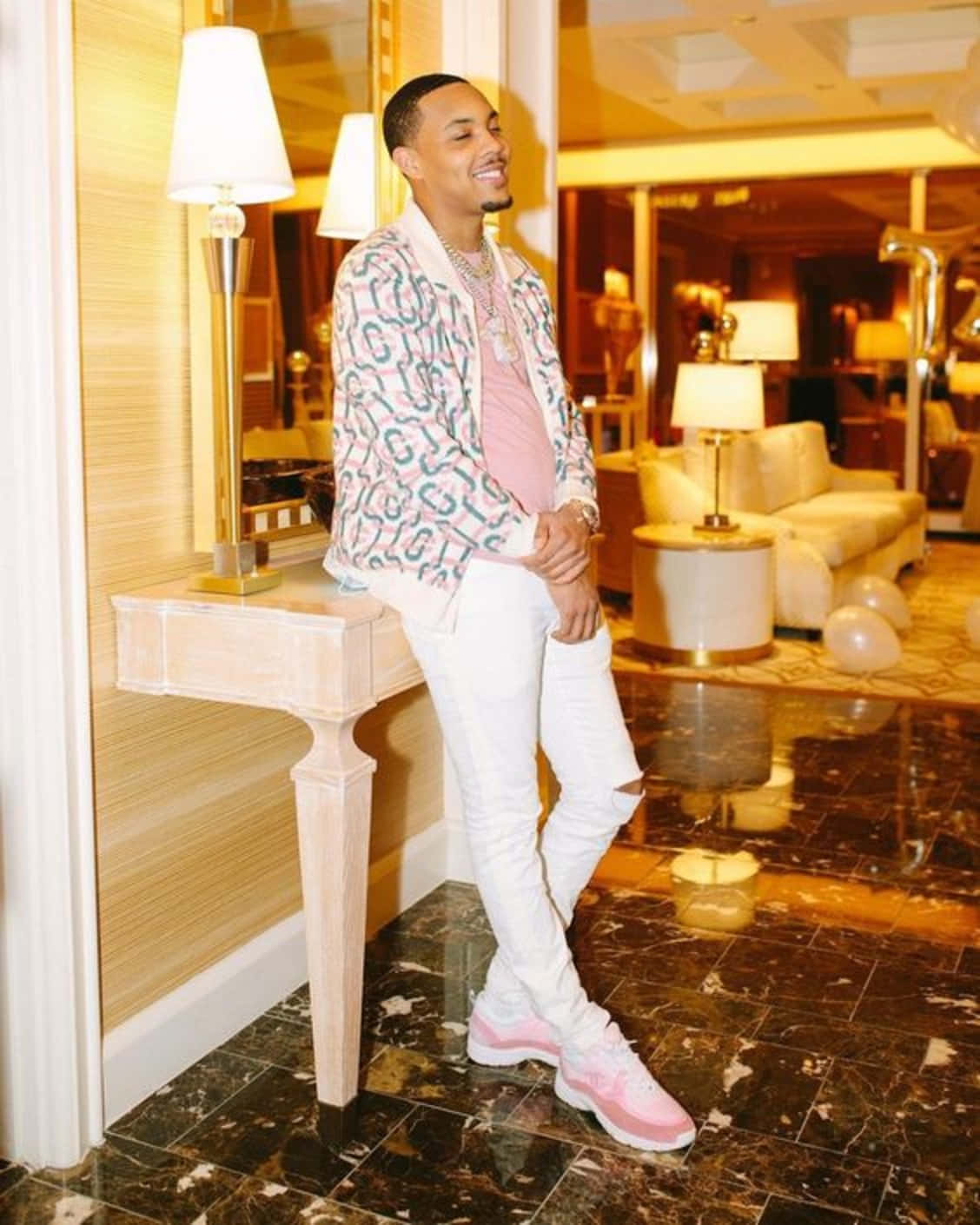 A Man In White Pants And Pink Jacket Standing In A Room Background