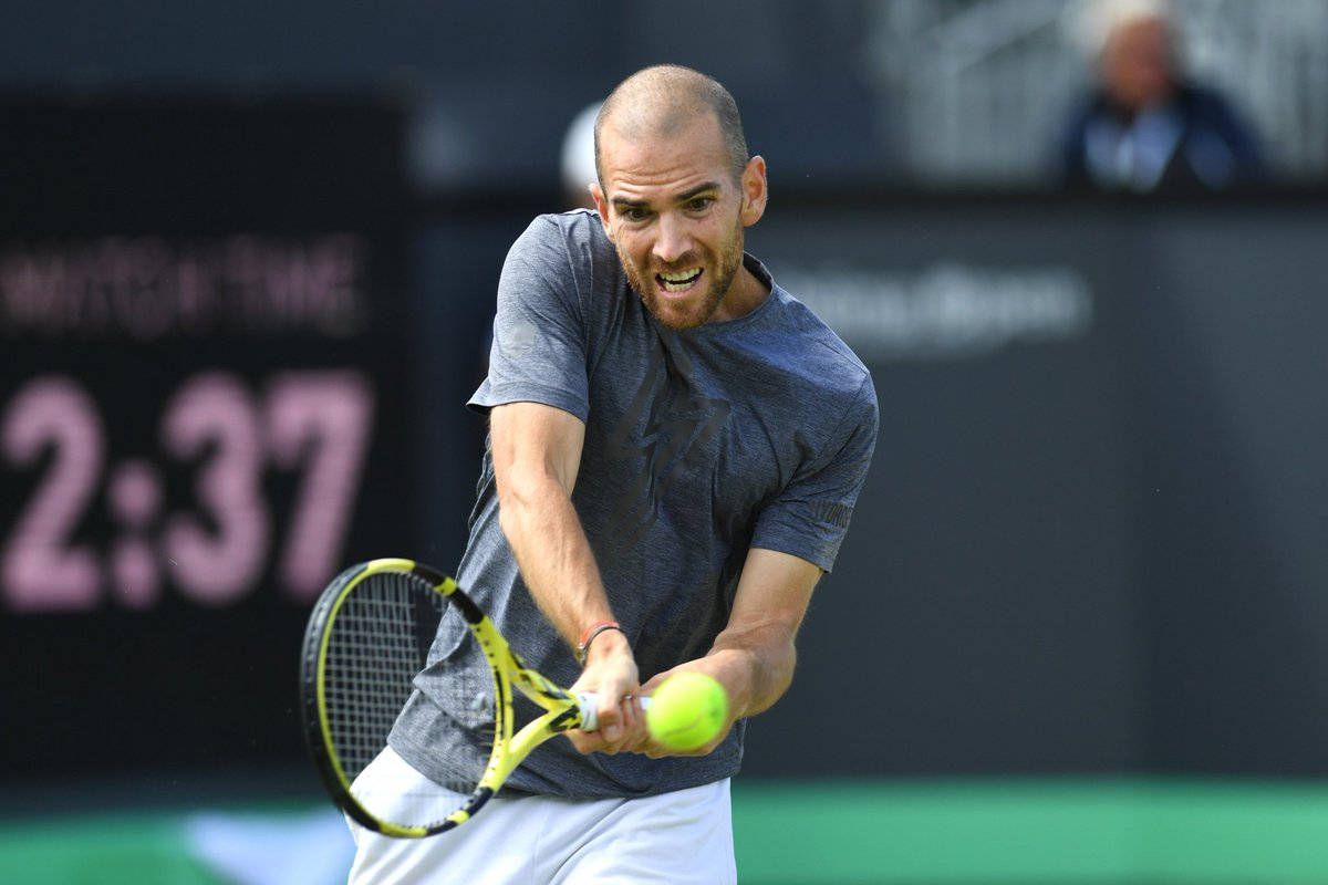 A Man Is Hitting A Tennis Ball Background