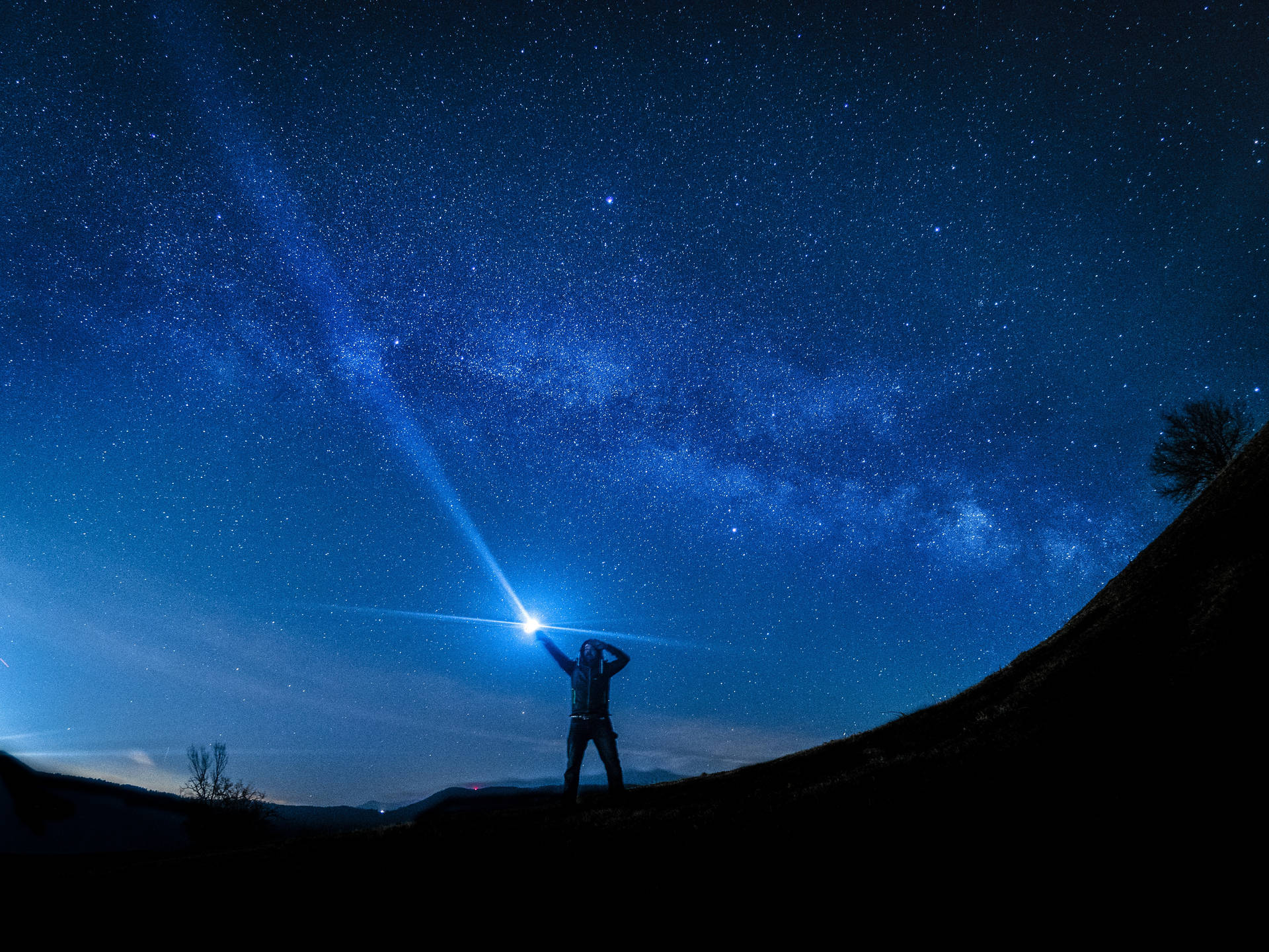 A Man Is Holding A Flashlight Under The Stars Background