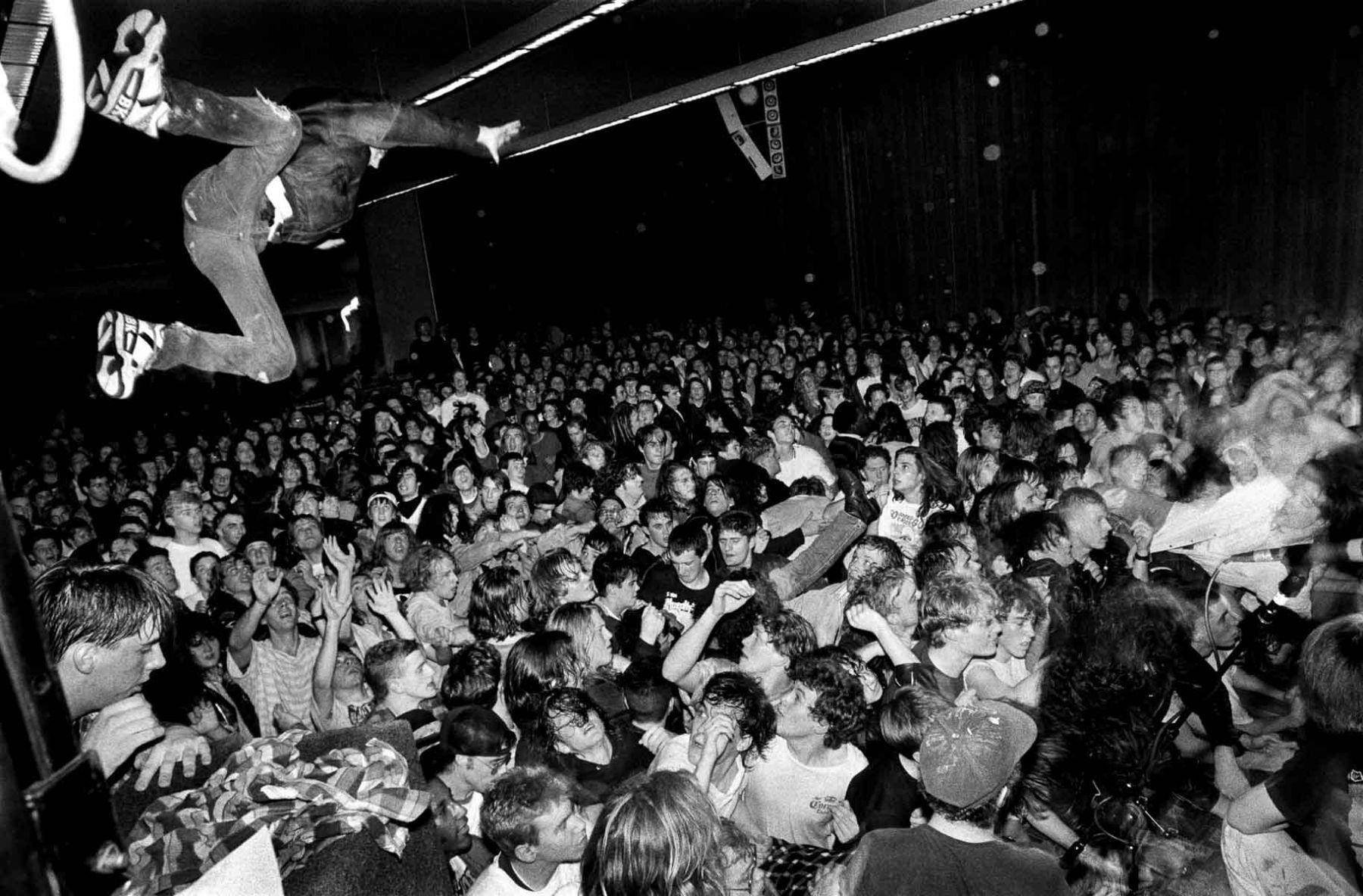 A Man Is Jumping Over A Crowd Of People Background
