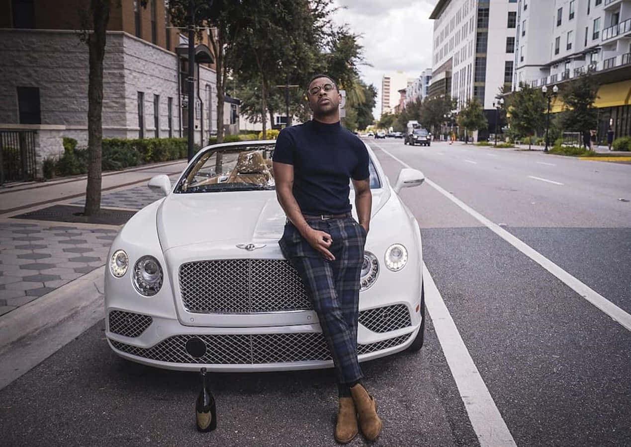 A Man Is Leaning On A Bentley Continental Background