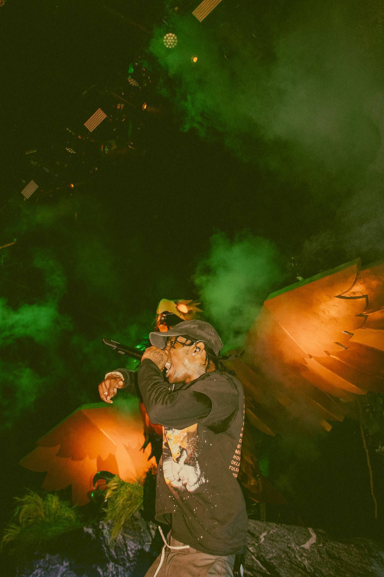 A Man Is On Stage With Smoke Coming Out Of His Mouth Background