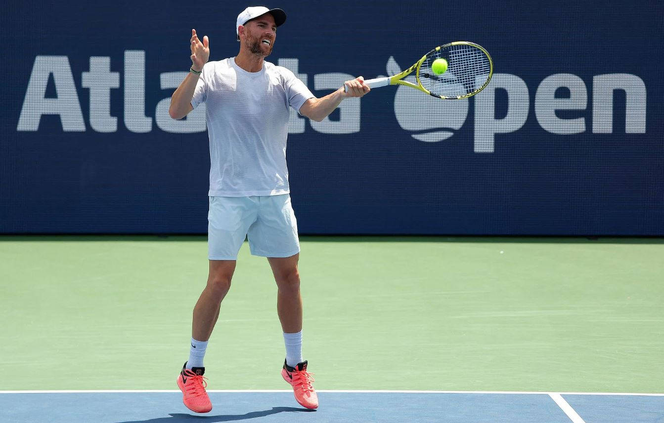 A Man Is Playing Tennis On A Tennis Court