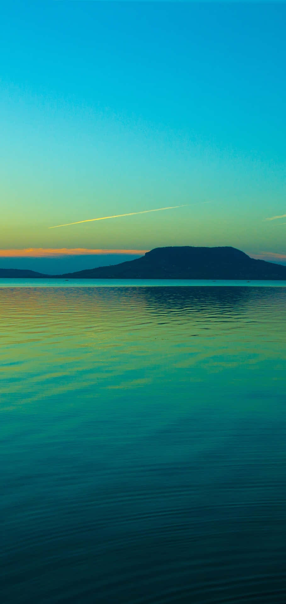 A Man Is Riding A Boat On A Lake At Sunset Background