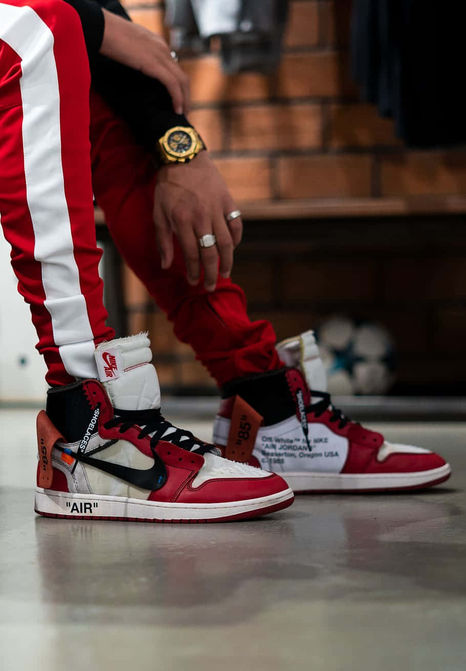 A Man Is Sitting On A Red And White Air Jordan 1 Background