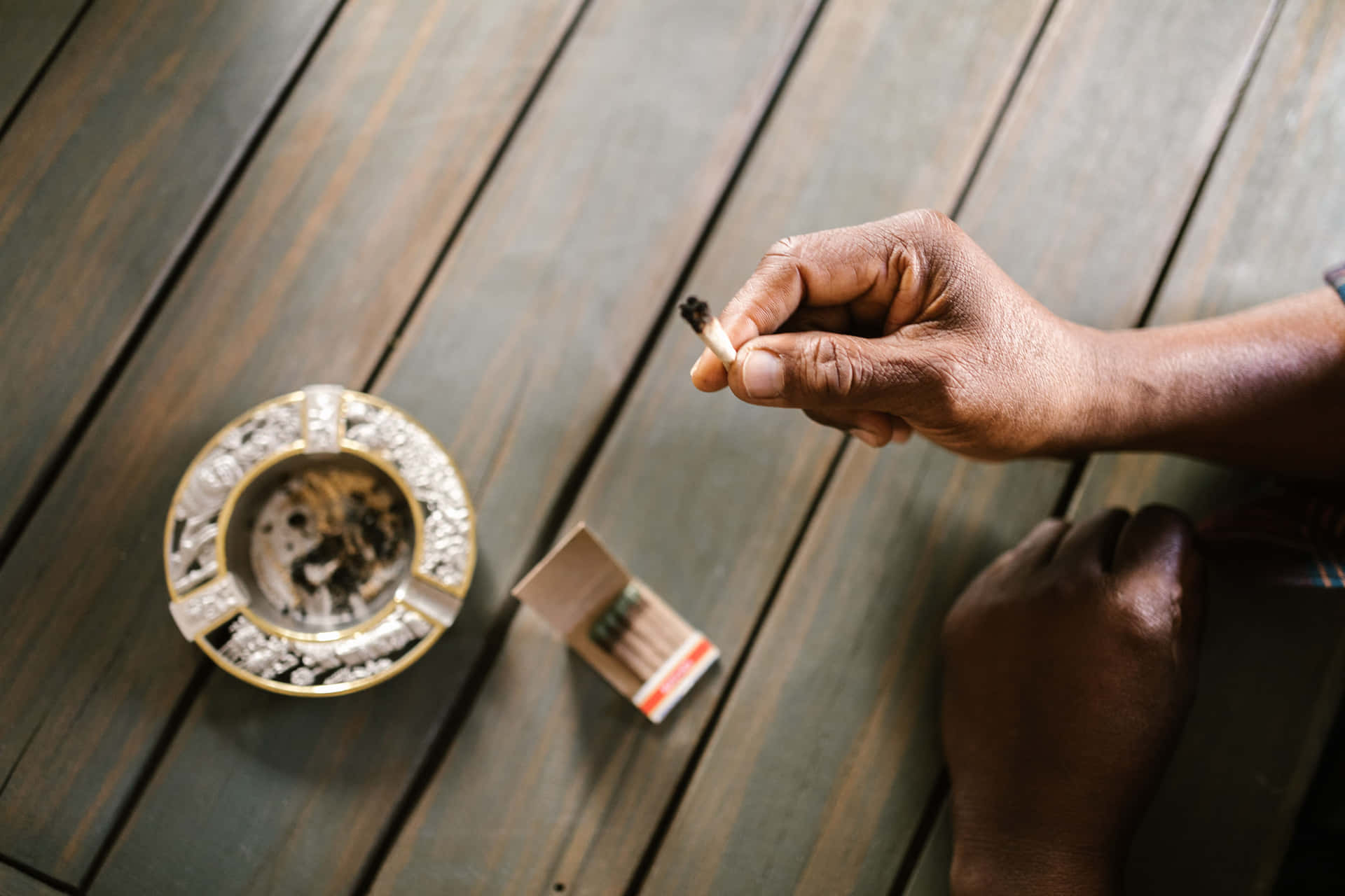 A Man Is Smoking A Cigarette On A Wooden Table Background