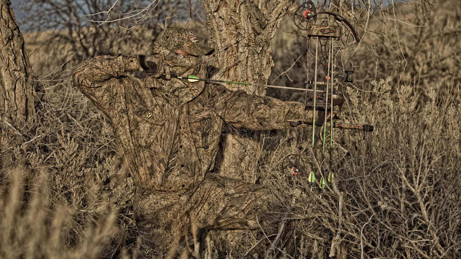 A Man Is Standing In The Grass With A Bow Background