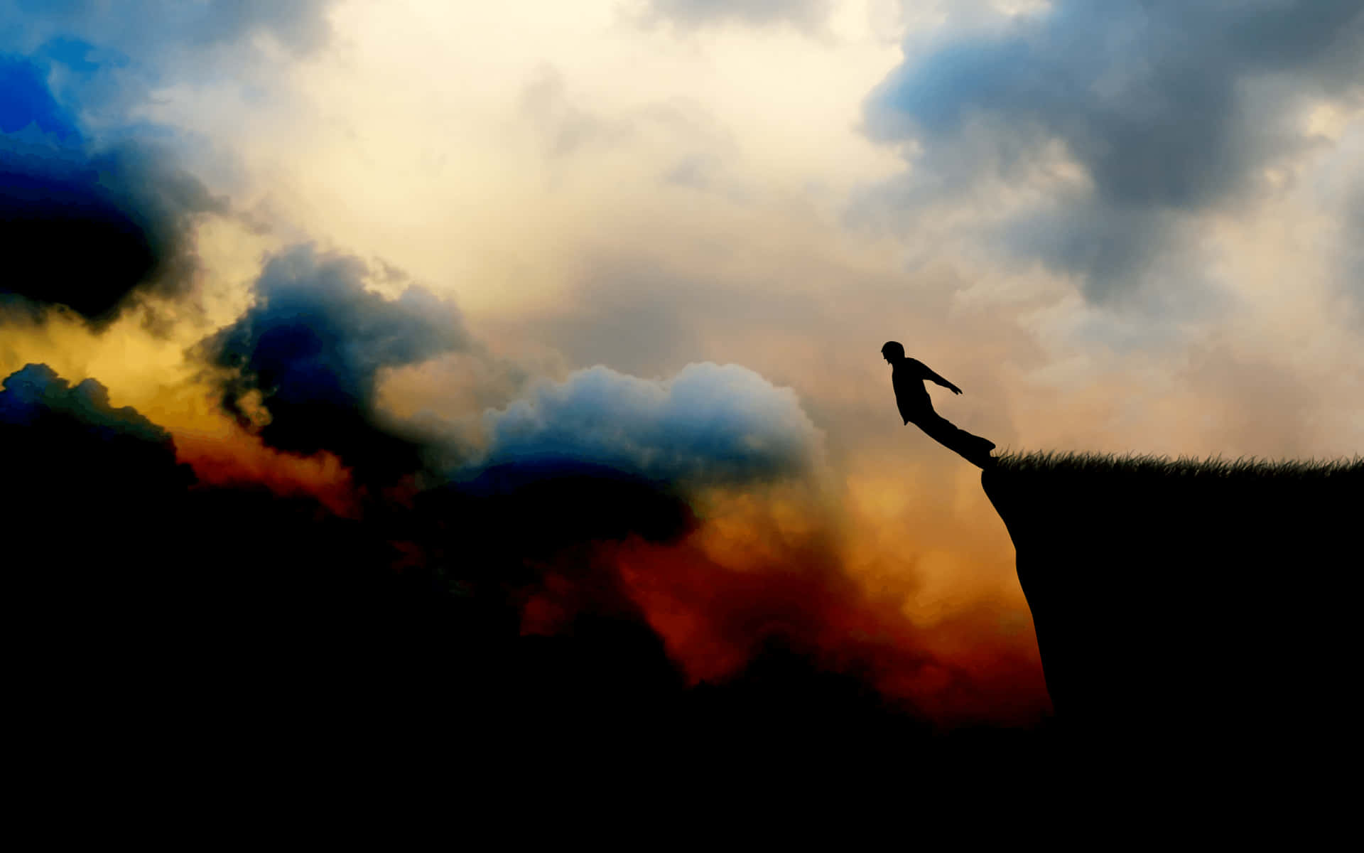 A Man Is Standing On A Cliff With Clouds In The Background