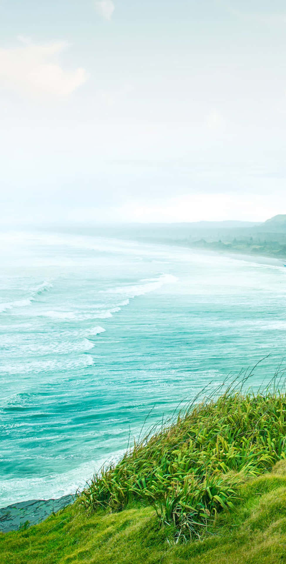 A Man Is Standing On A Hill Overlooking The Ocean Background