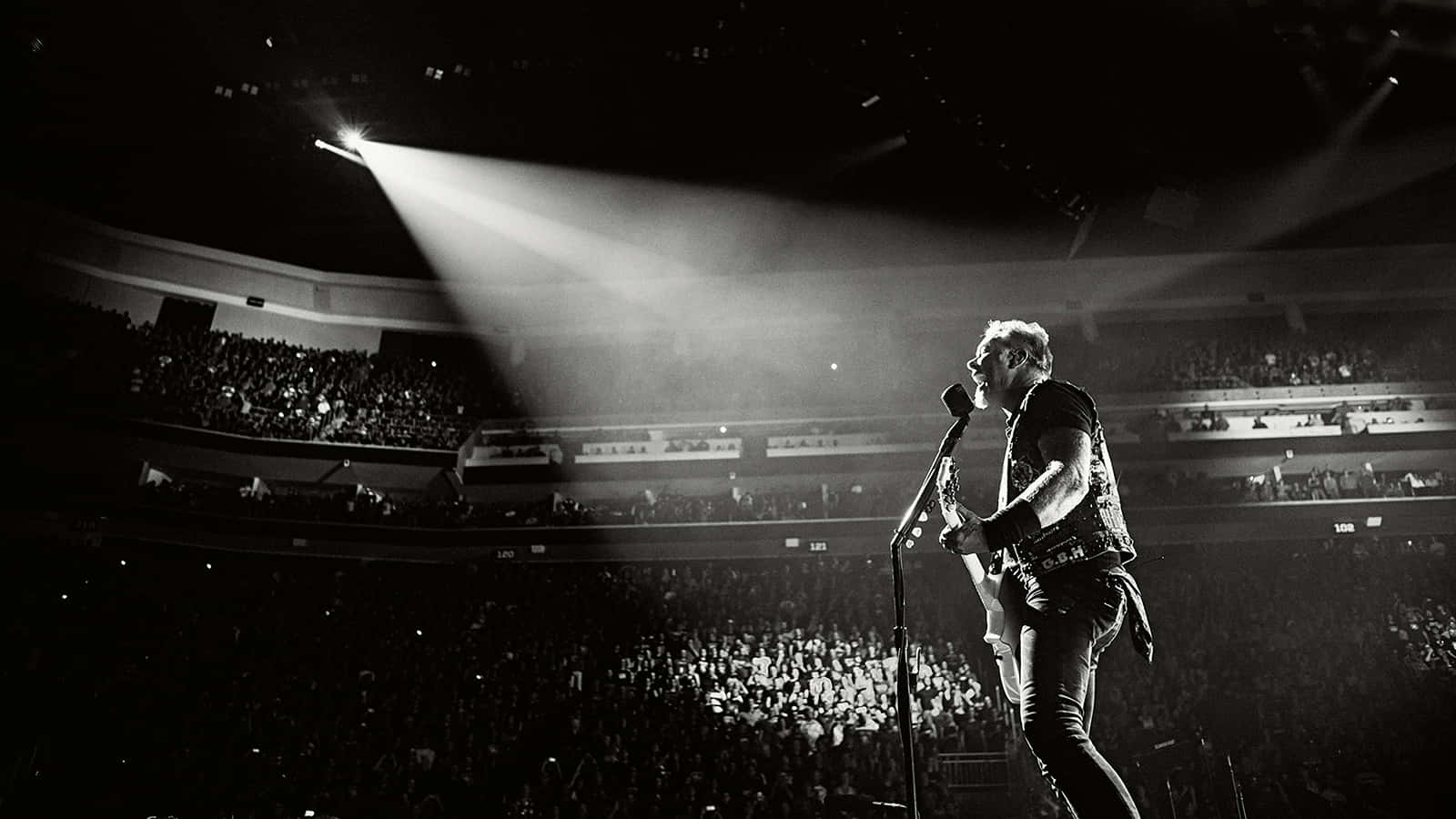 A Man Is Standing On Stage In Front Of A Spotlight