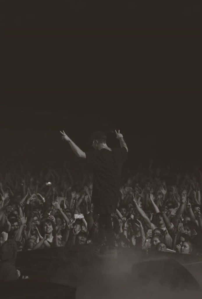 A Man Is Standing On Stage With His Arms Raised Background