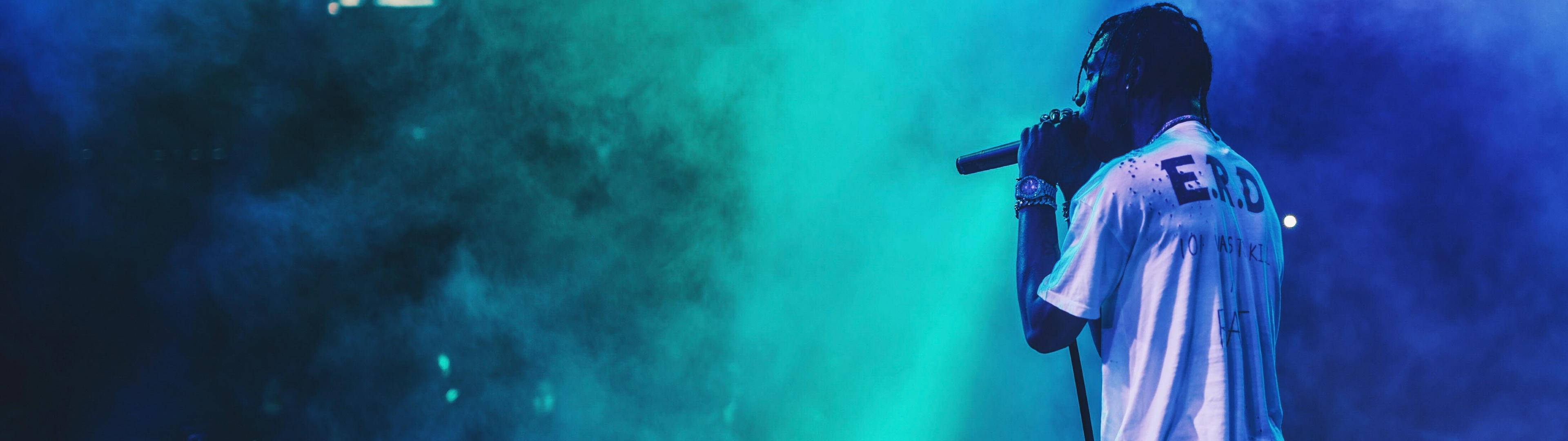 A Man Is Standing On Stage With Smoke Coming Out Of His Mouth Background