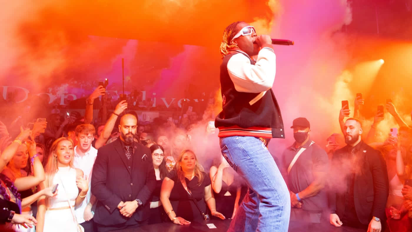 A Man Is Standing On Stage With Smoke Coming Out Of His Mouth Background