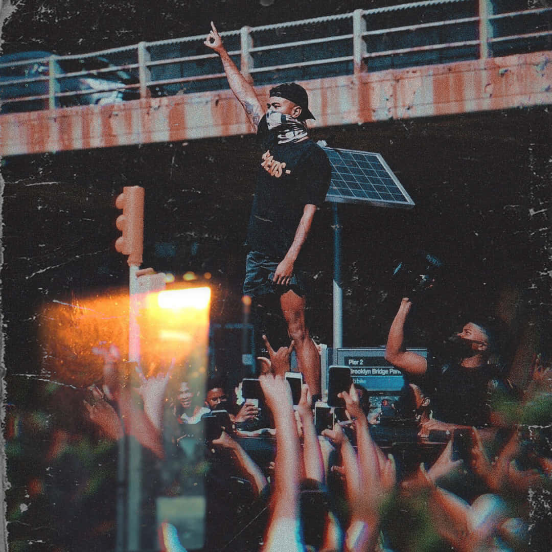 A Man Is Standing On Top Of A Crowd Of People Background