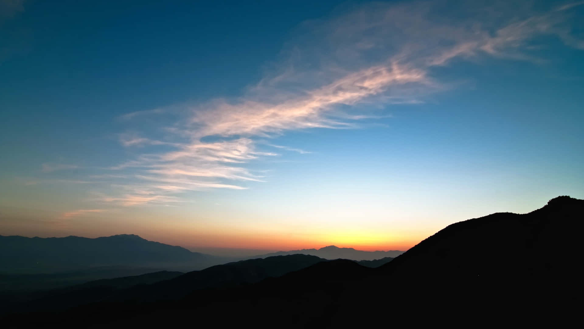 A Man Is Standing On Top Of A Mountain At Sunset Background