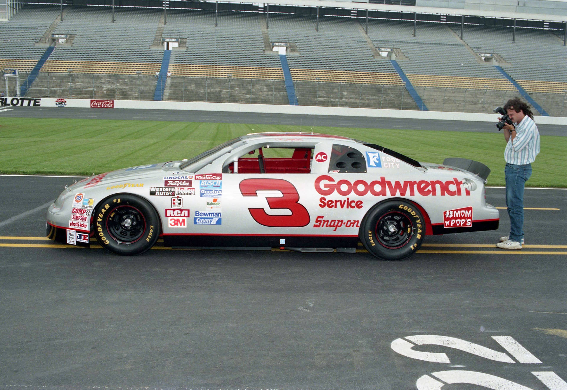 A Man Is Taking Pictures Of A Nascar Car Background