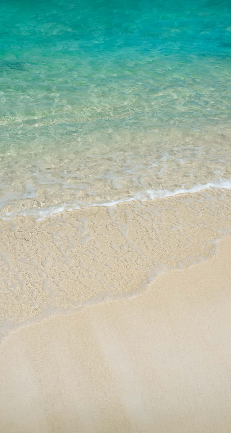 A Man Is Walking On A Sandy Beach With Water Background