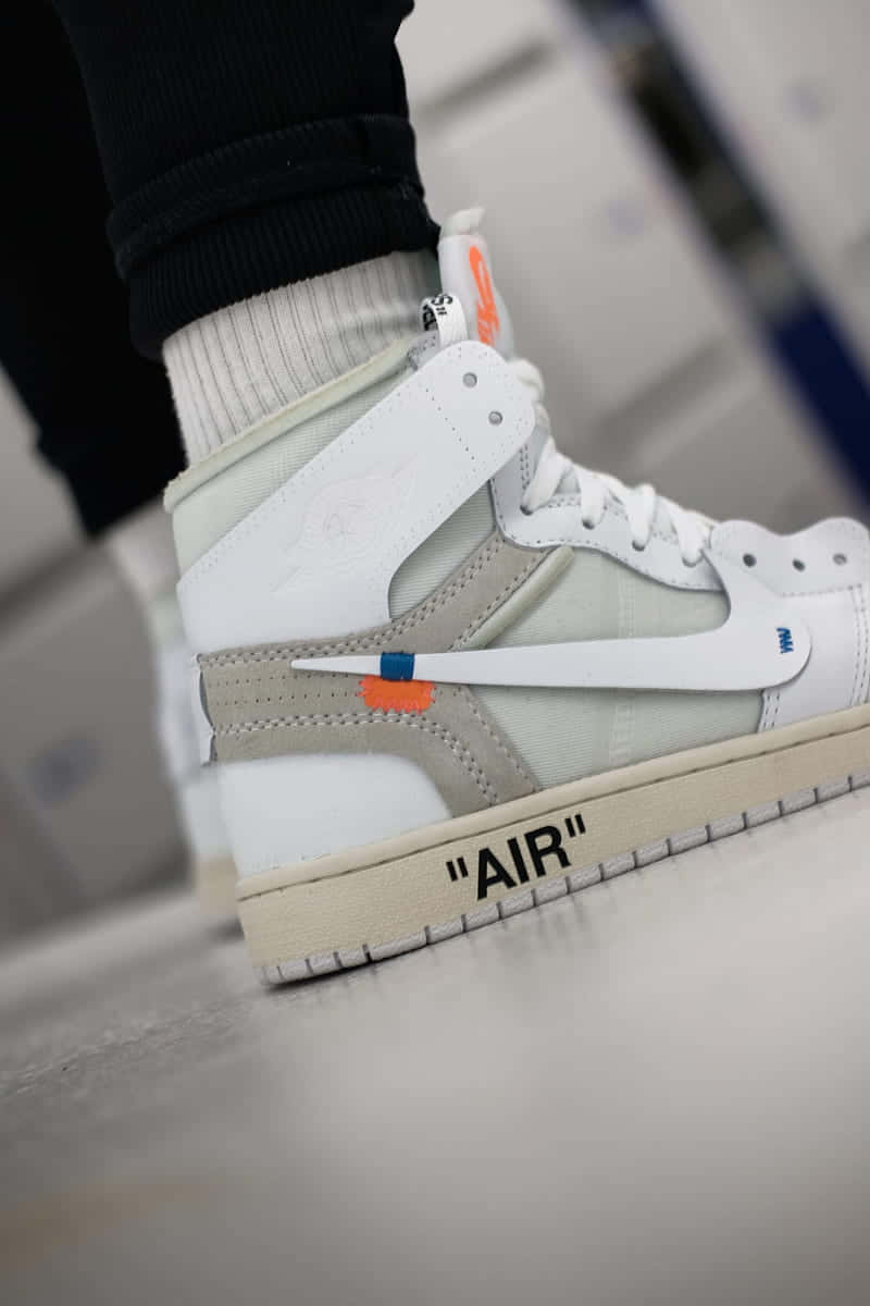 A Man Is Wearing A White - Off - White - Air Jordan 1 Mid Background