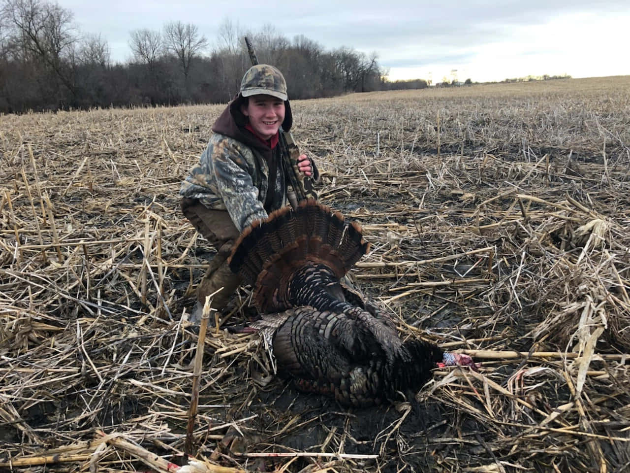 A Man Kneeling Down In A Field With A Turkey Background