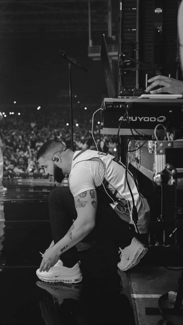 A Man Kneeling On The Floor While A Man Is Playing A Keyboard Background