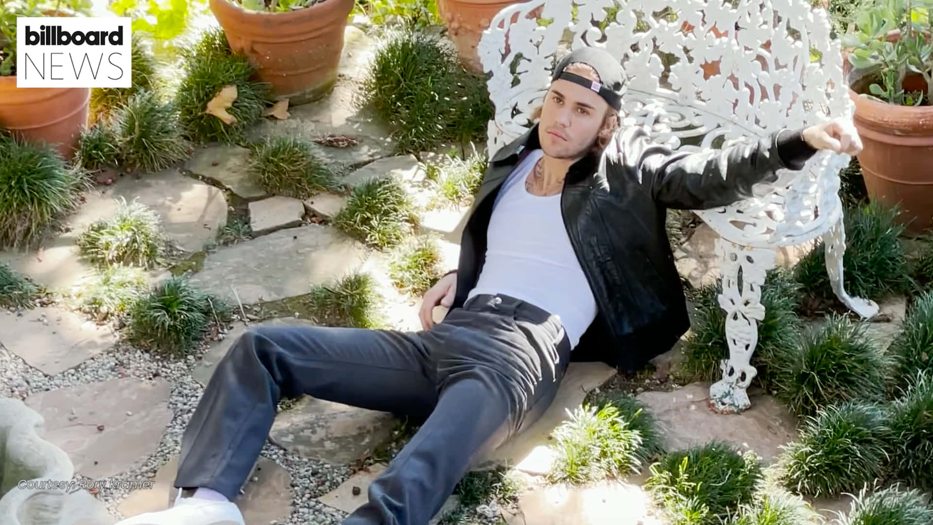 A Man Laying On A White Bench In A Garden Background
