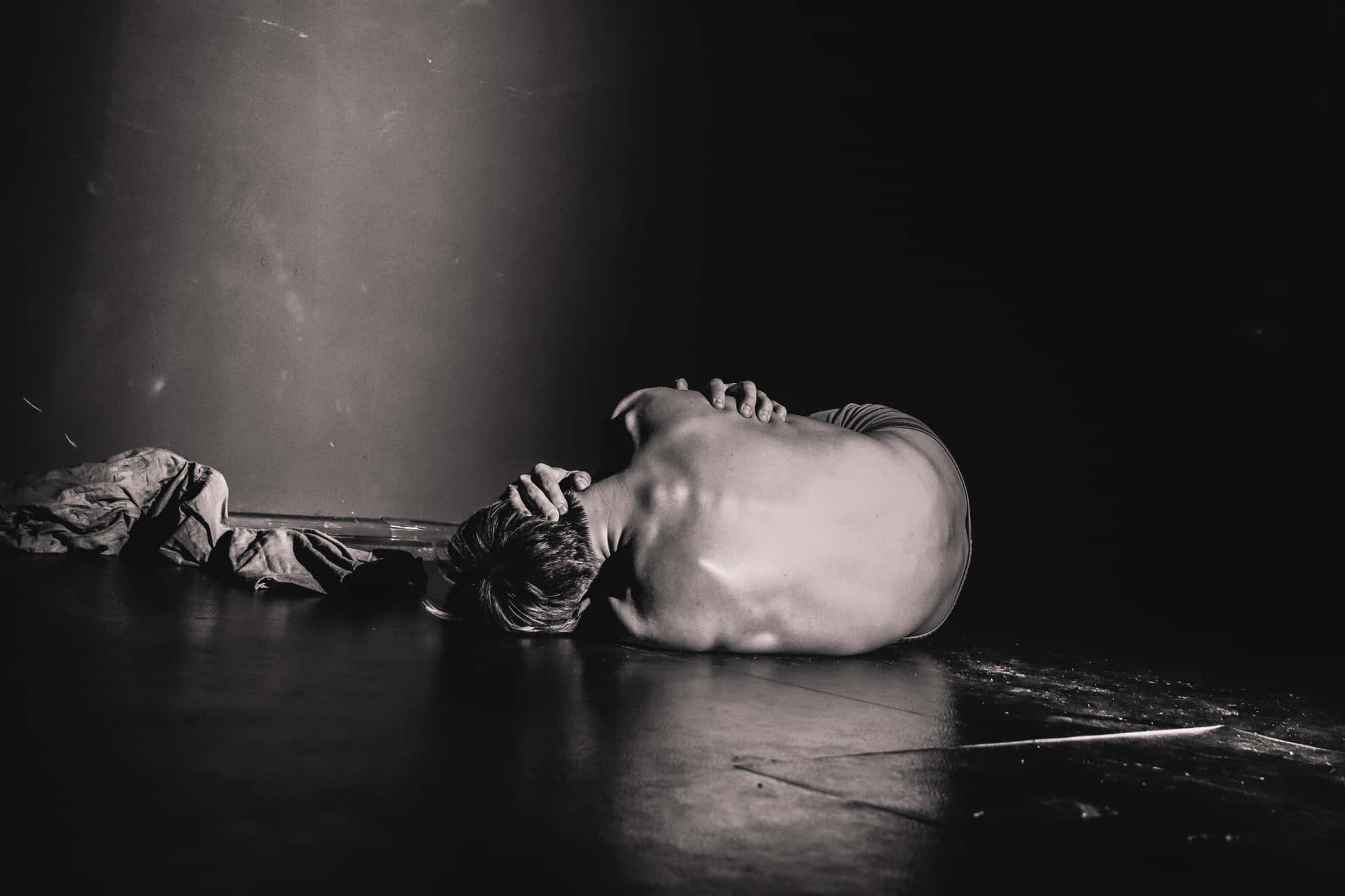 A Man Laying On The Floor With His Head Down Background