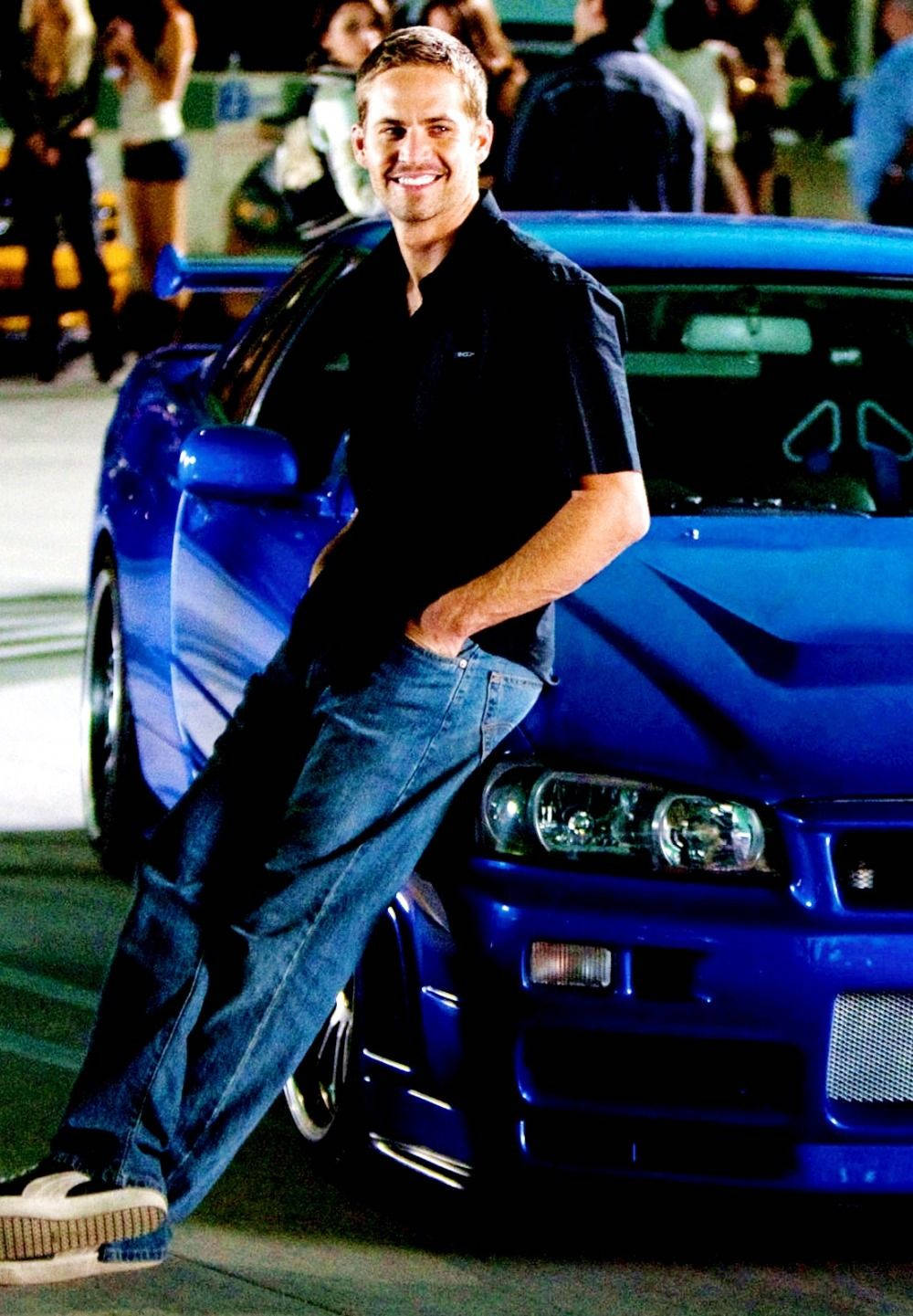 A Man Leaning On A Blue Sports Car Background