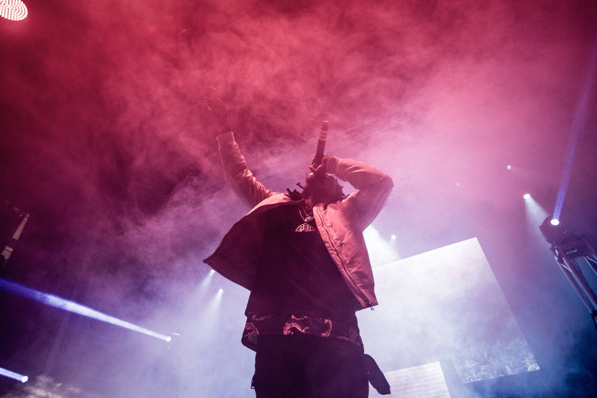 A Man On Stage With Smoke Coming Out Of His Mouth Background