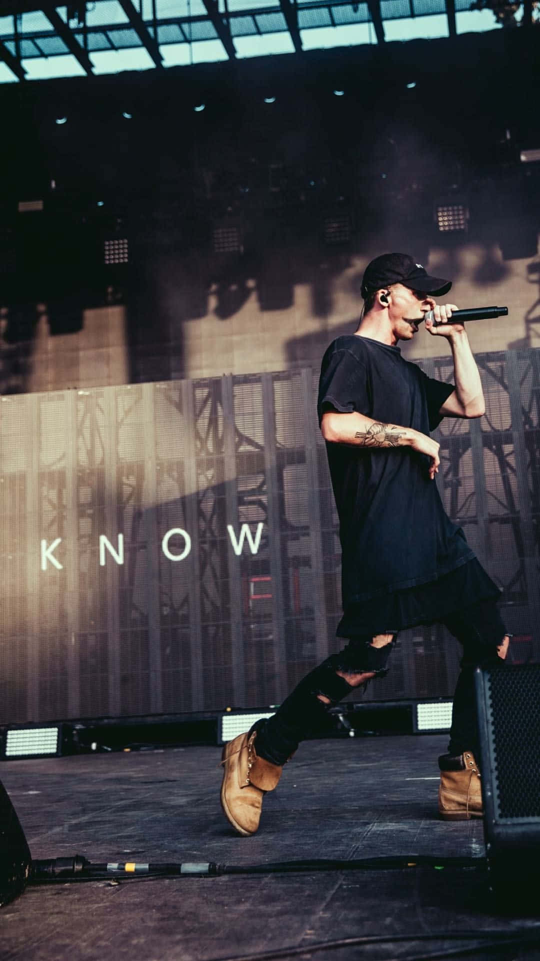 A Man On Stage With The Words Know Background