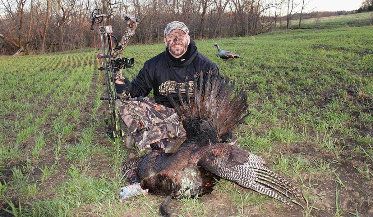 A Man Posing With A Turkey In The Field Background