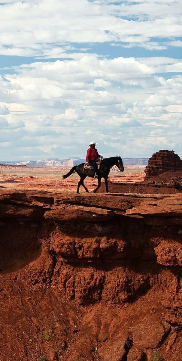 A Man Riding A Horse On A Cliff