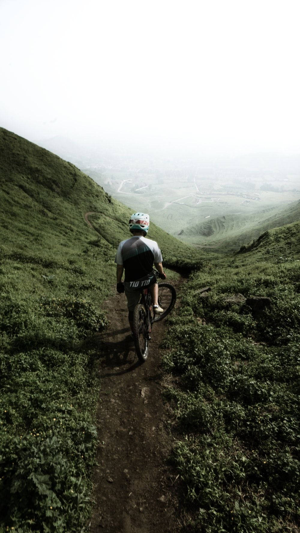 A Man Riding A Mountain Bike On A Green Hill Background