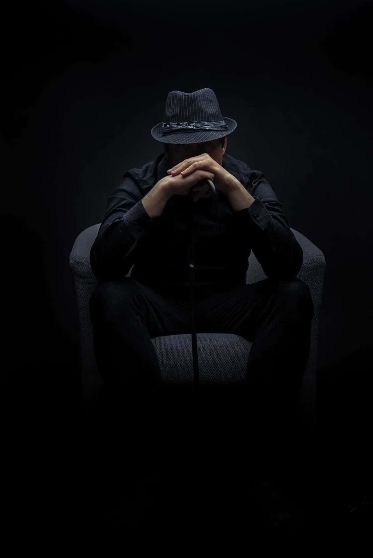 A Man Sitting In A Chair Background