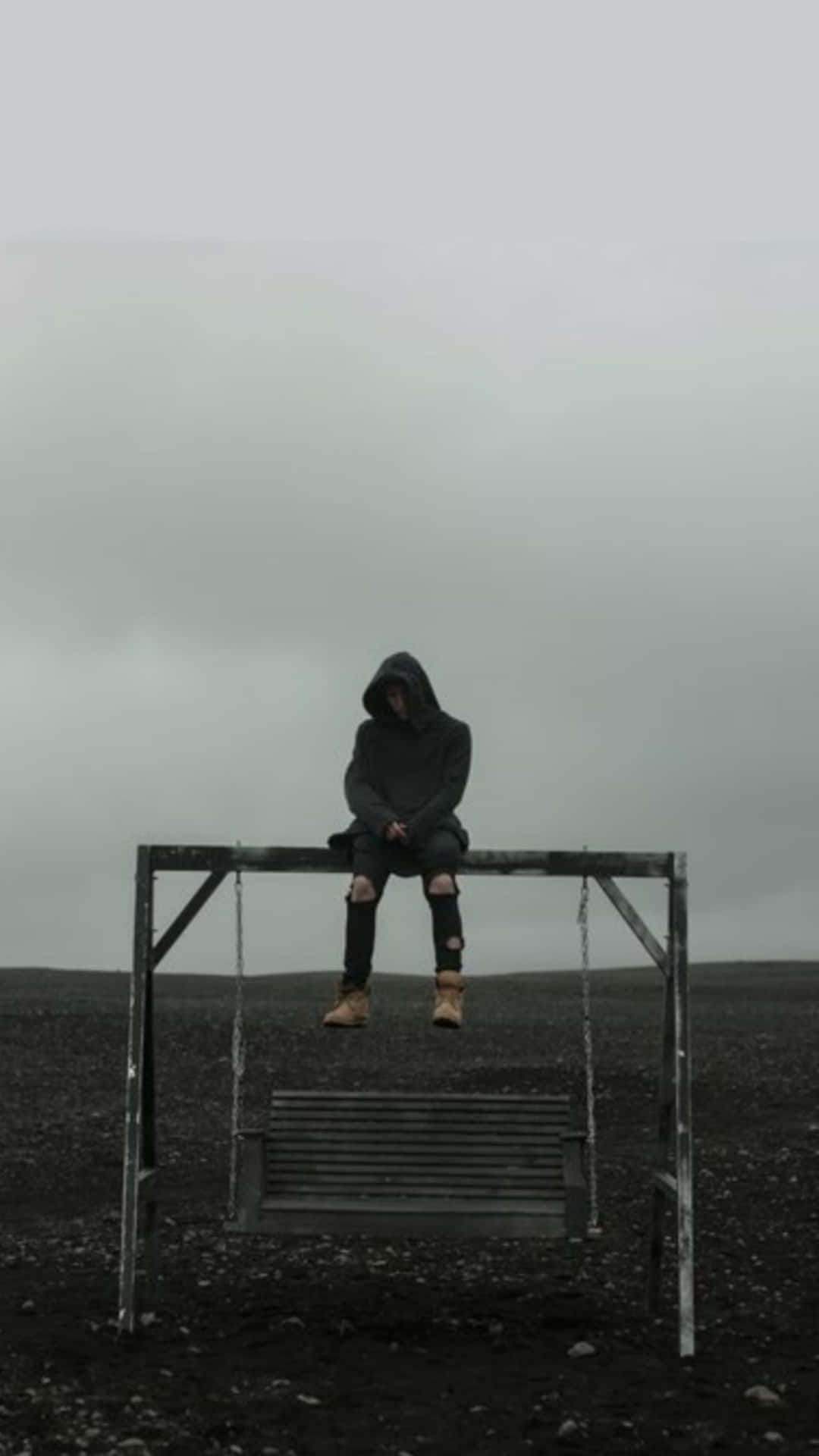 A Man Sitting On A Bench In A Field Background