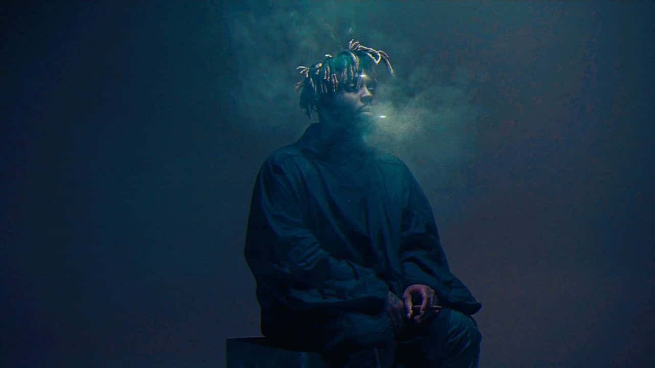 A Man Sitting On A Box With Smoke Coming Out Of His Mouth Background