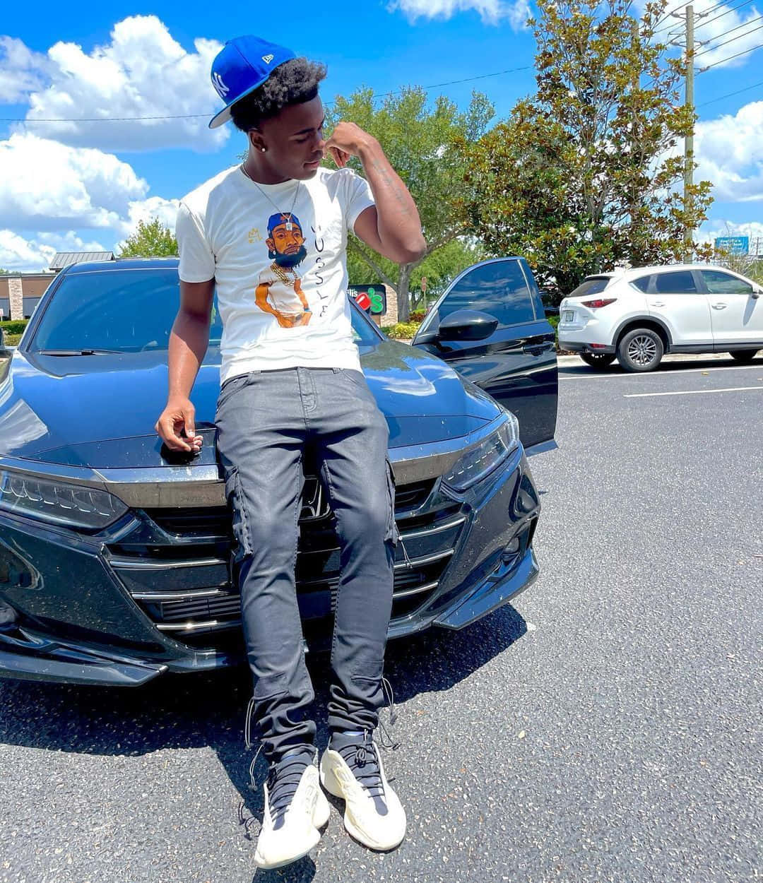 A Man Sitting On The Side Of A Black Car Background