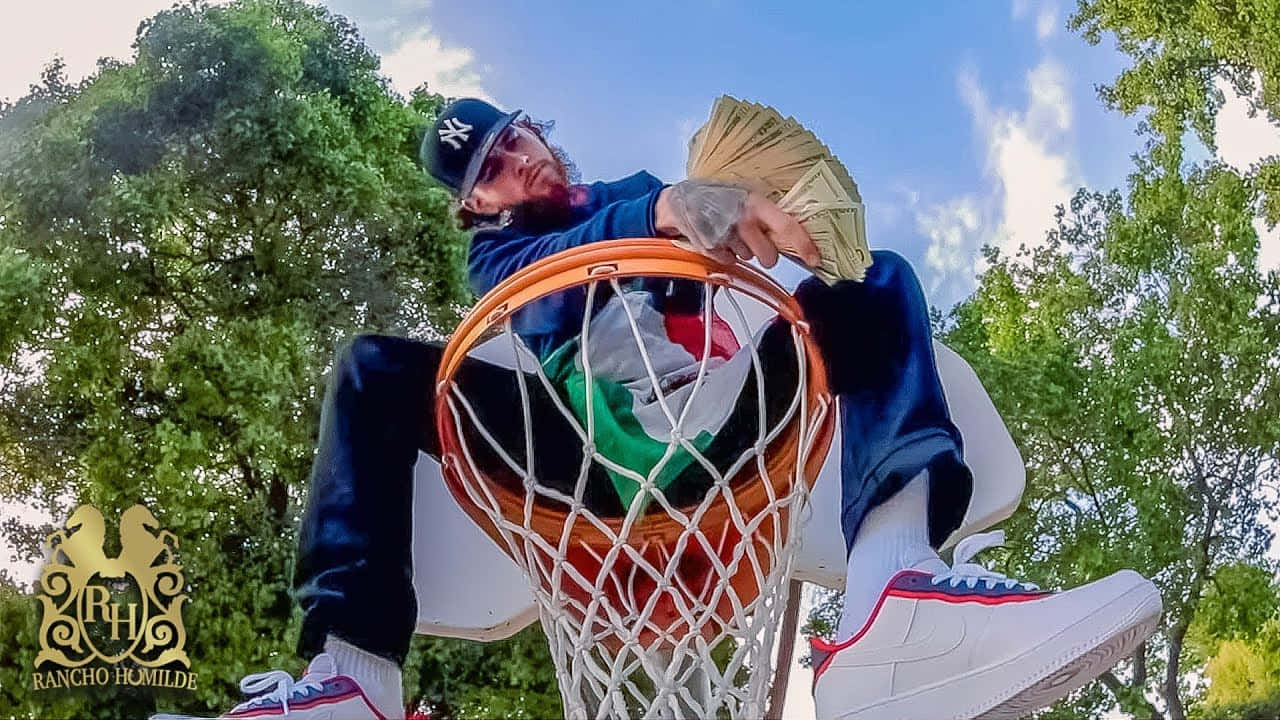 A Man Sitting On Top Of A Basketball Hoop Background