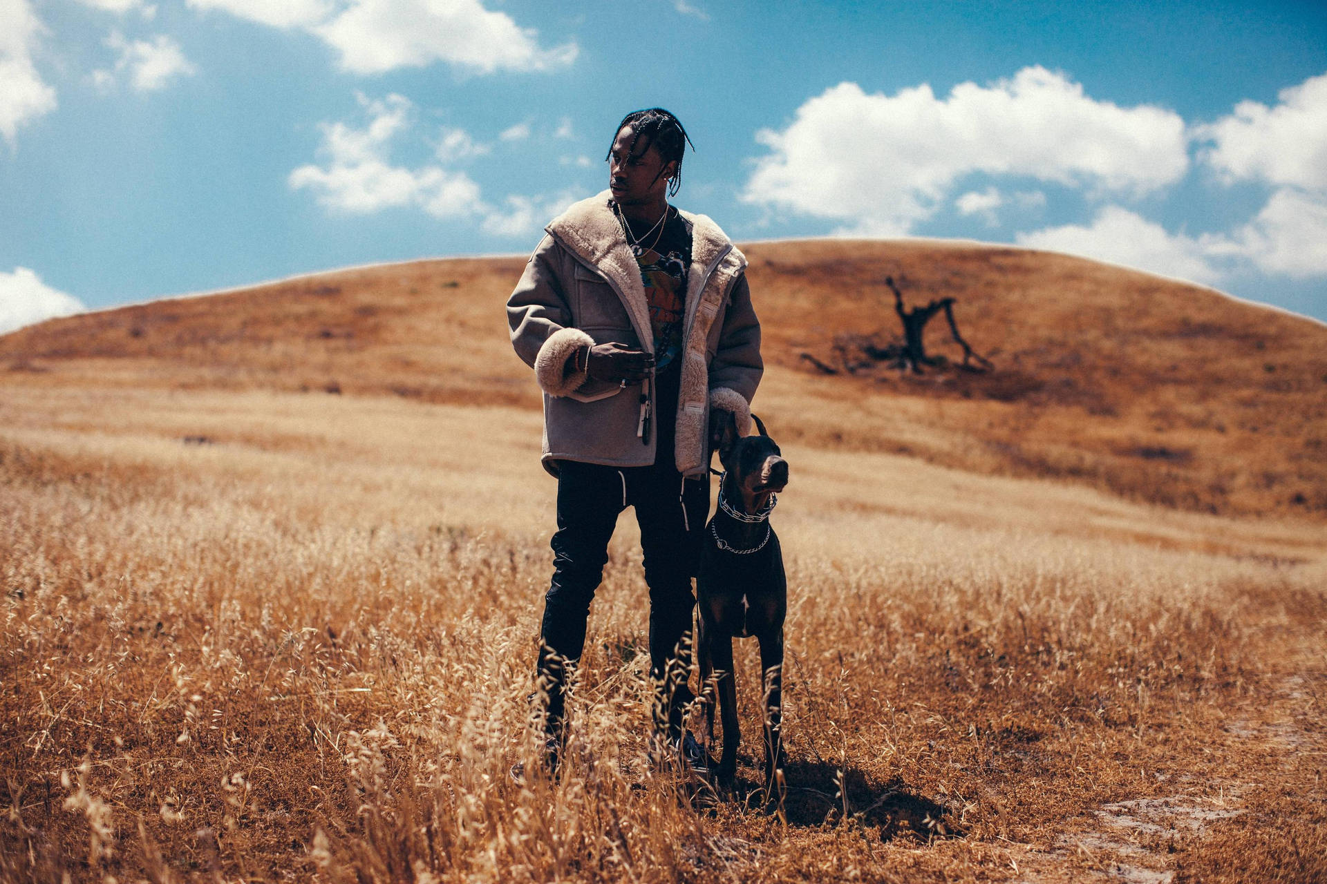 A Man Standing In A Field With His Dog Background