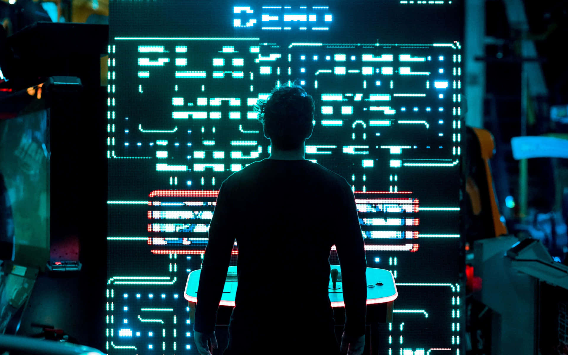 A Man Standing In Front Of A Large Electronic Game Background