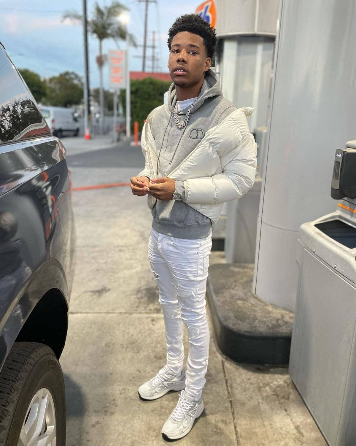 A Man Standing Next To A Car At A Gas Station Background