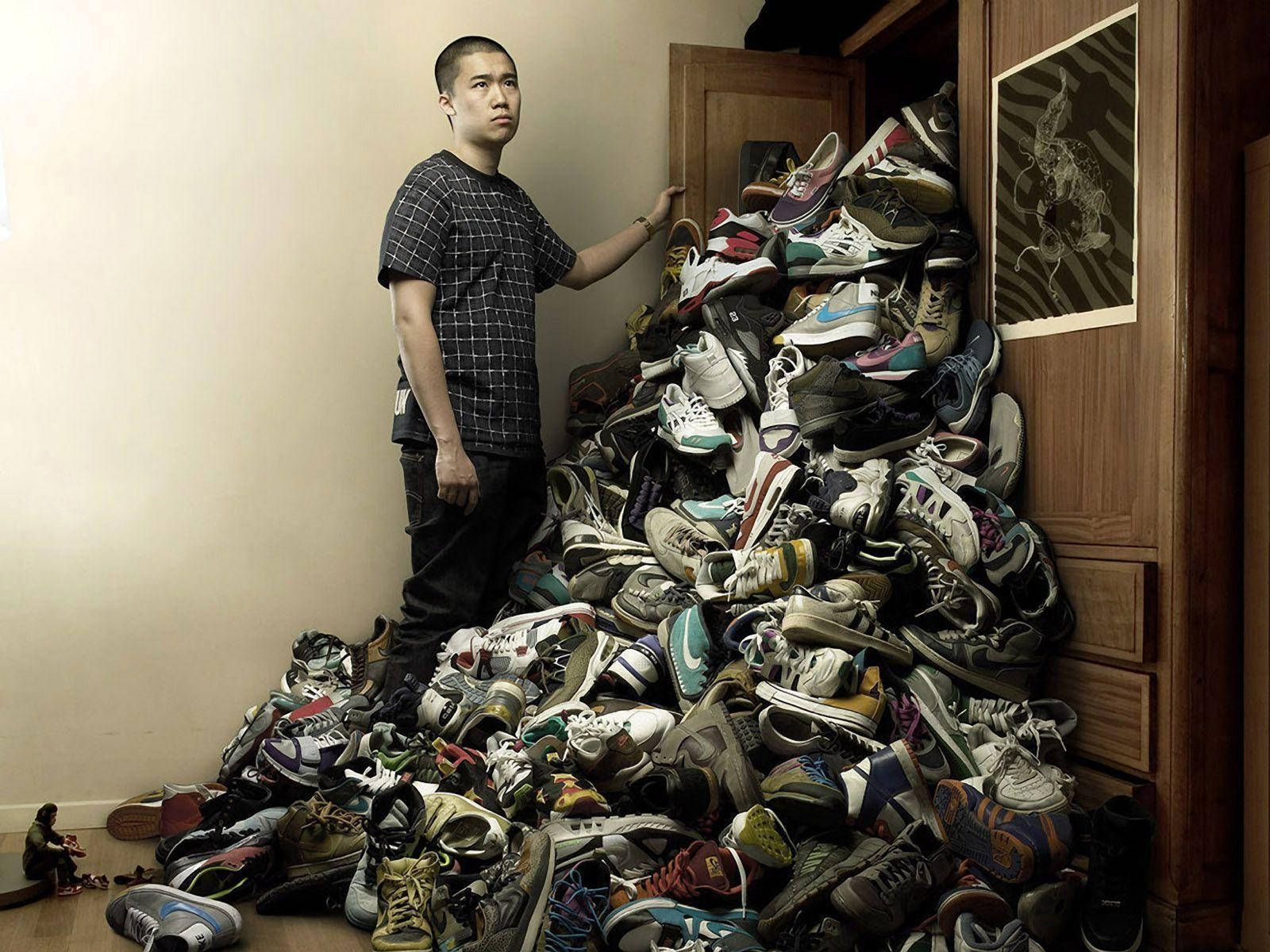 A Man Standing Next To A Pile Of Shoes