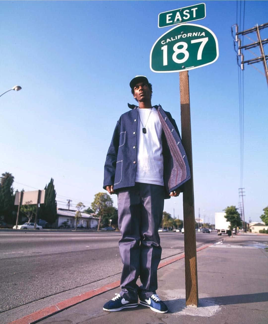 A Man Standing Next To A Street Sign Background