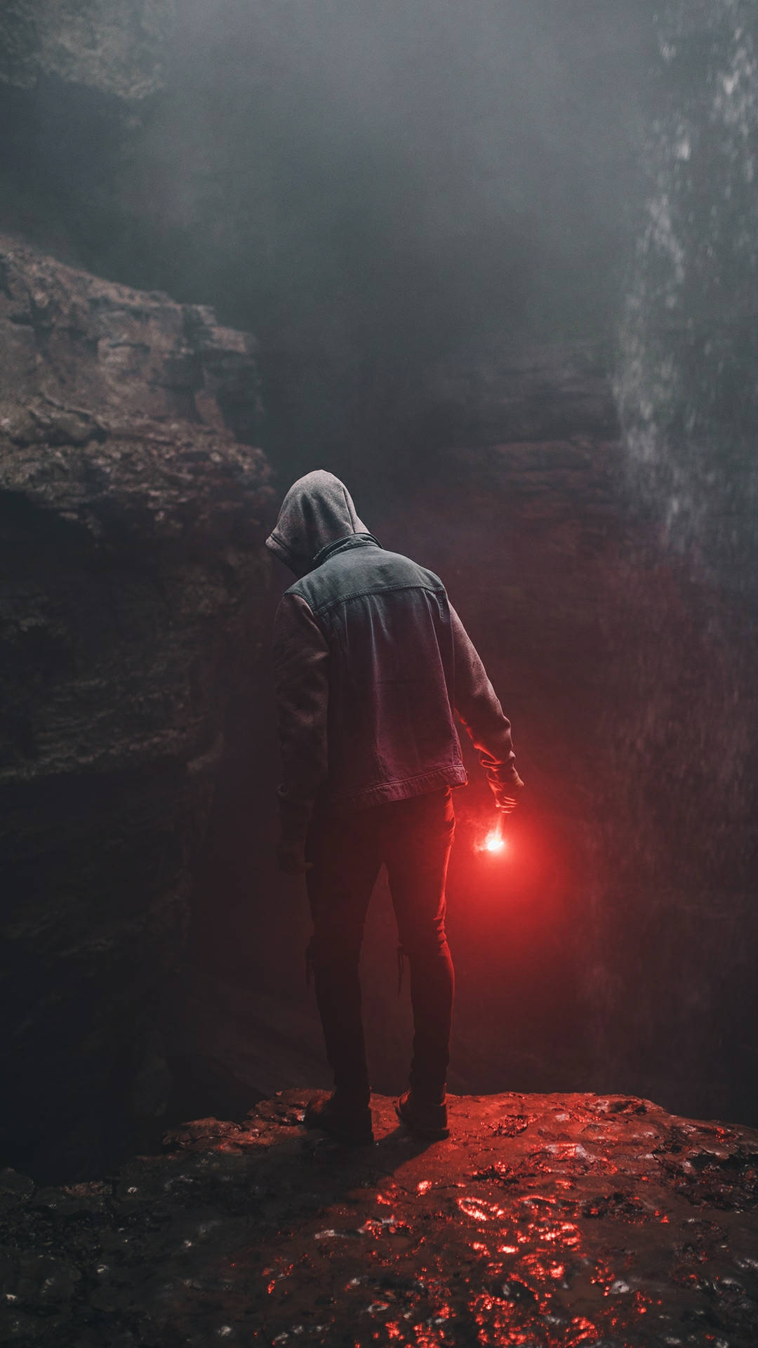 A Man Standing On A Cliff With A Flashlight Background