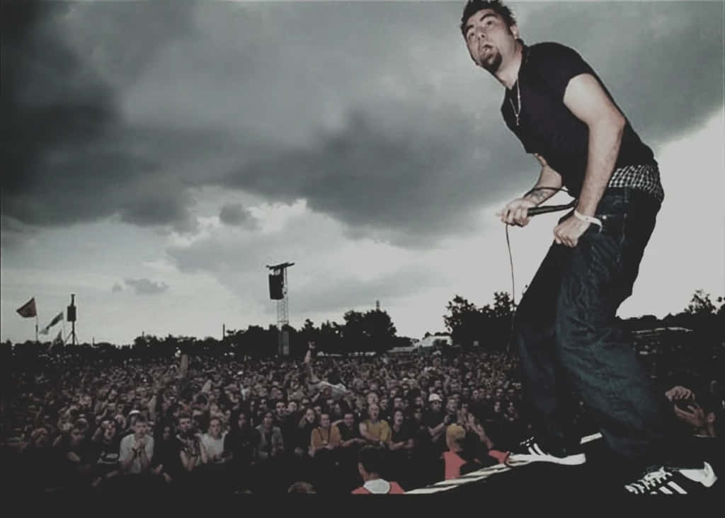 A Man Standing On Stage With A Microphone Background