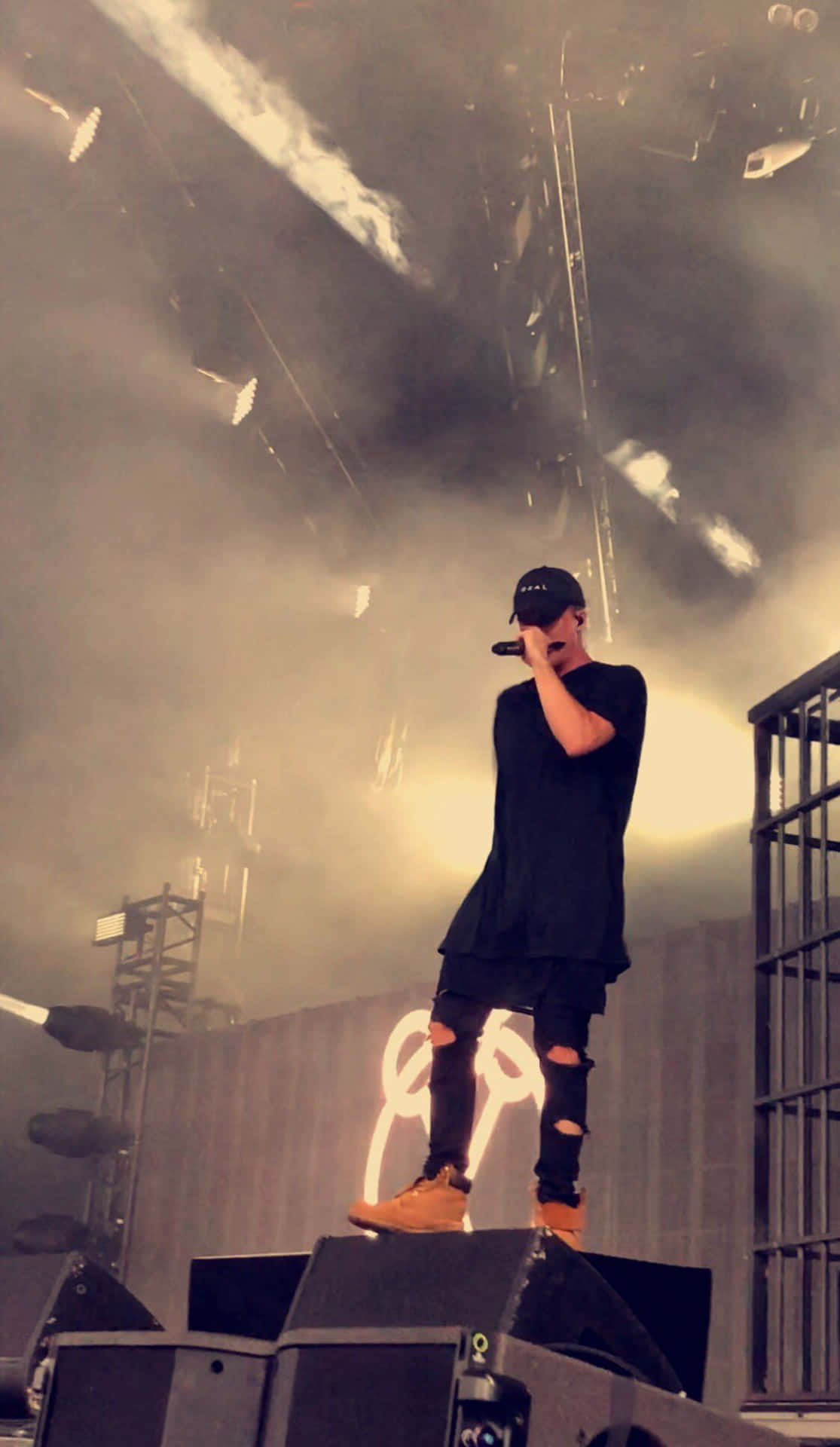 A Man Standing On Stage With A Microphone Background