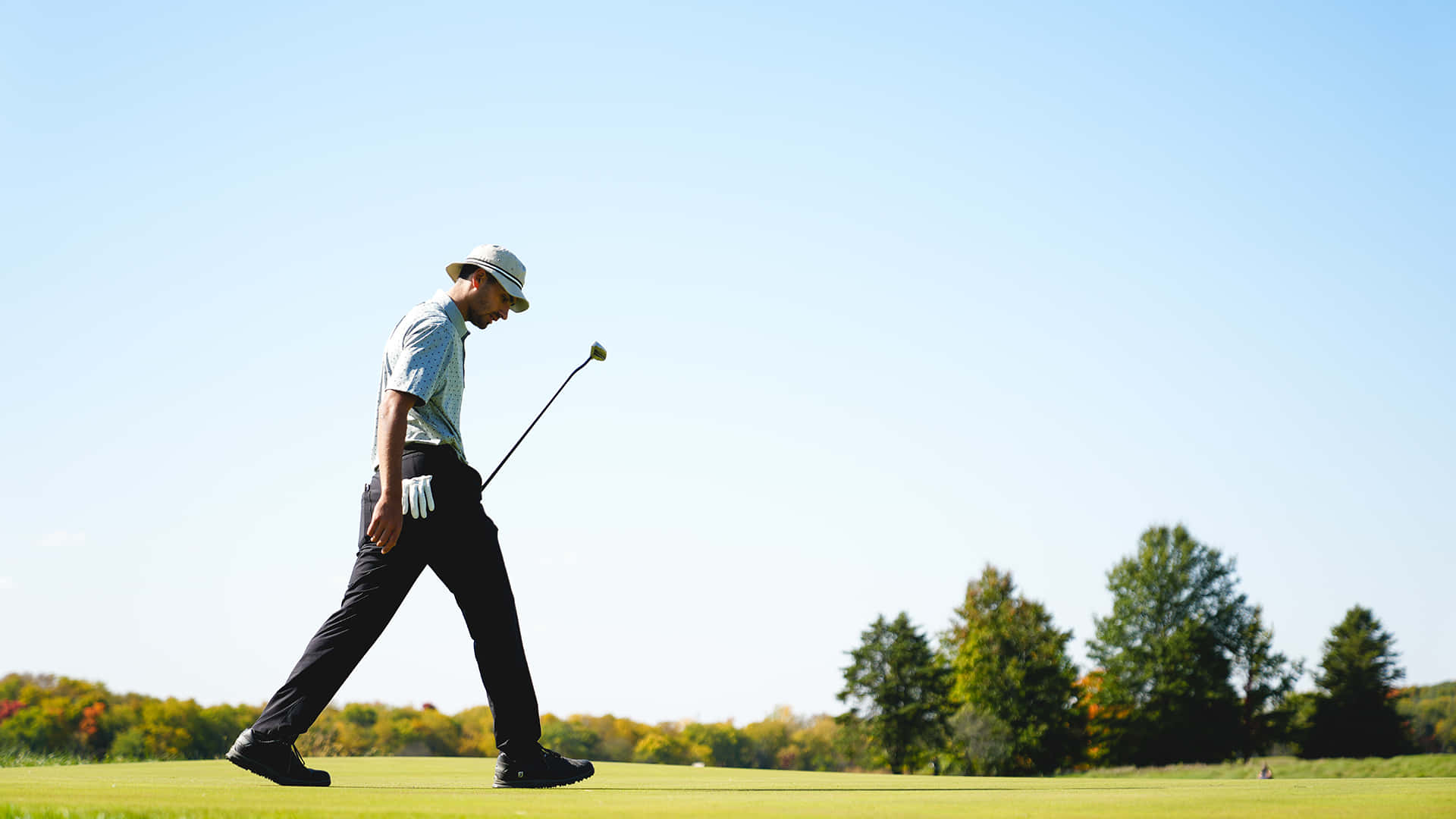 A Man Walking Across A Golf Course Background