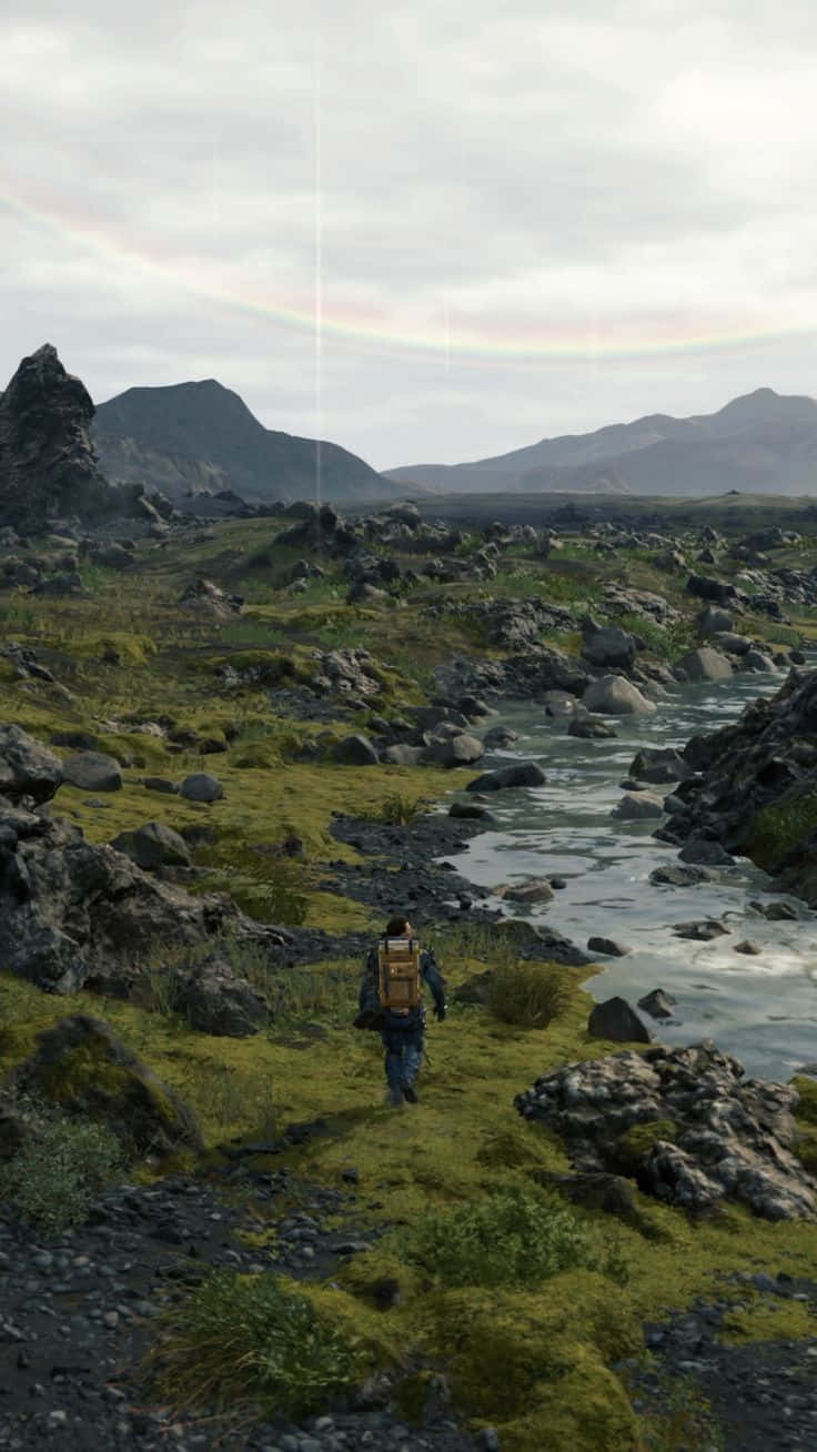 A Man Walking Through A Grassy Area With A Rainbow