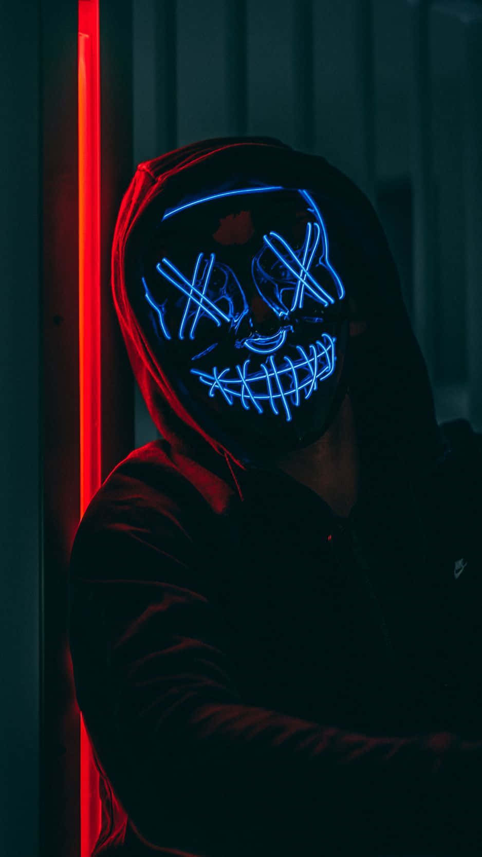 A Man Wearing A Neon Mask In A Dark Room Background