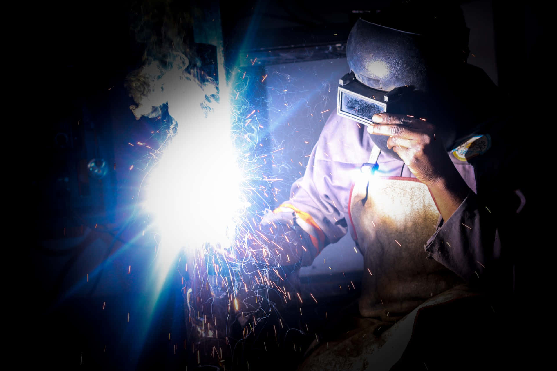 A Man Welding In The Dark Background